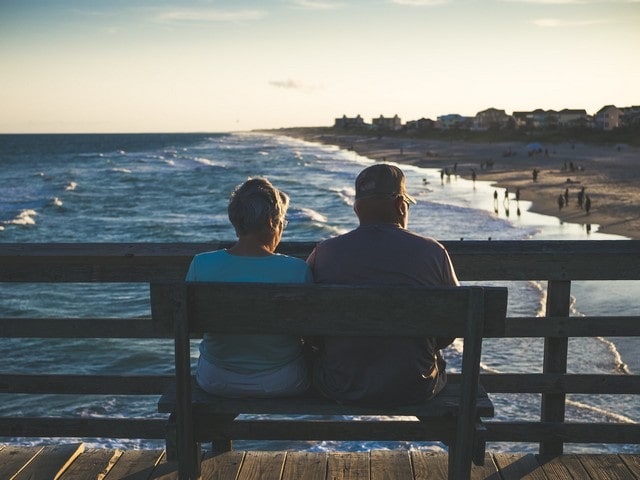 Elderly couple sitting on pier overlooking ocean after retirement in kentucky