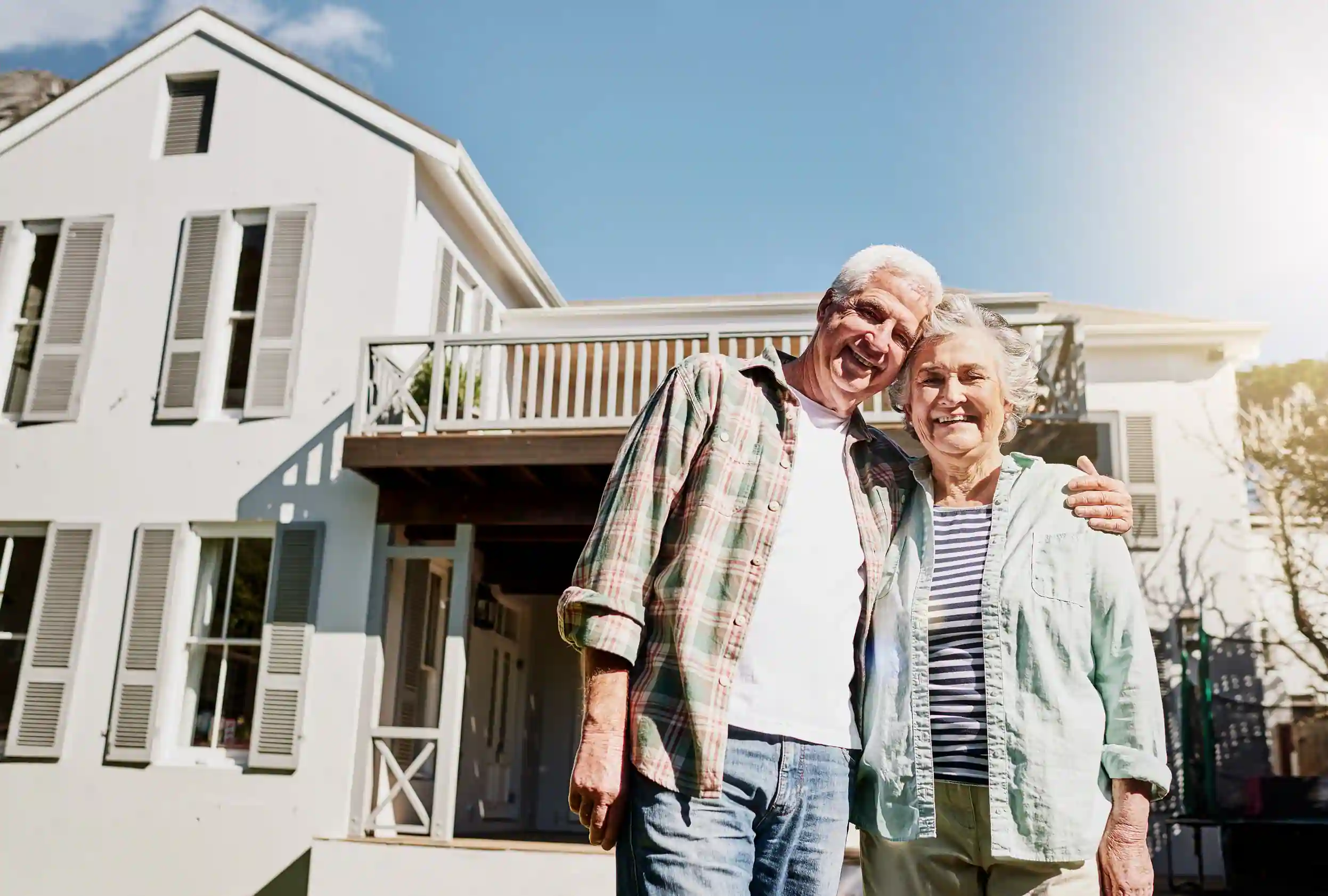 Happy senior couple standing outside their house