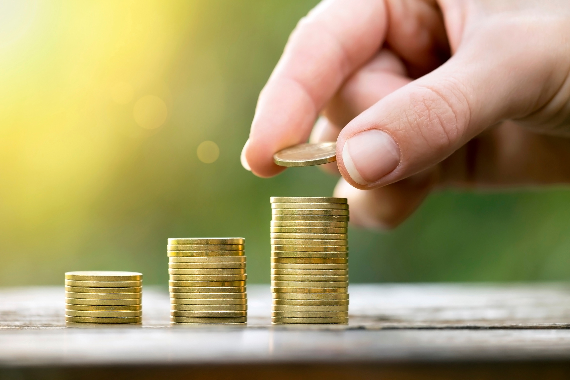 Hand stacking growing piles of gold coins