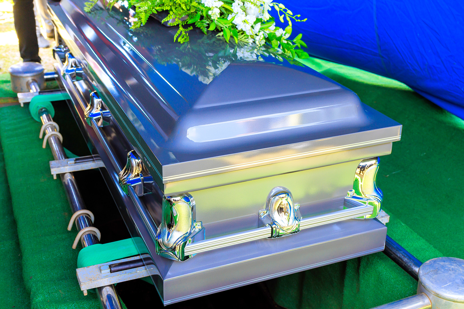Silver casket with flowers at burial site