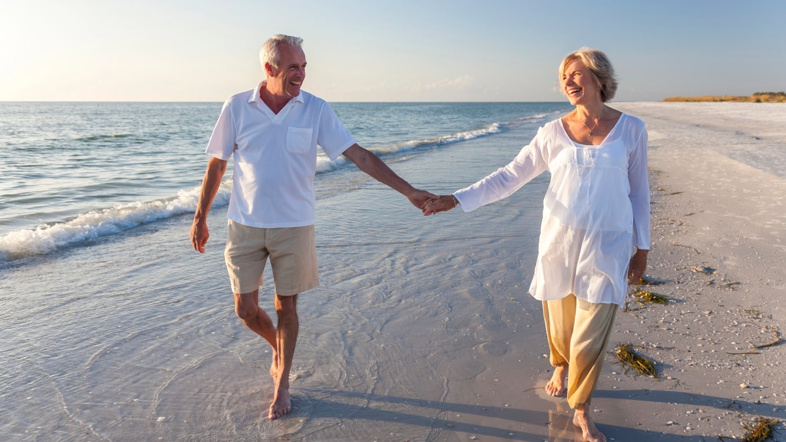 Senior couple walking together on the beach celebrating life insurance estate plan