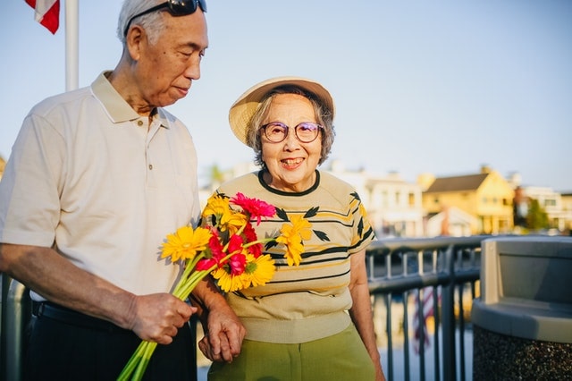 Elderly couple holding colorful flowers outdoors after reviewing estate plan in richmond