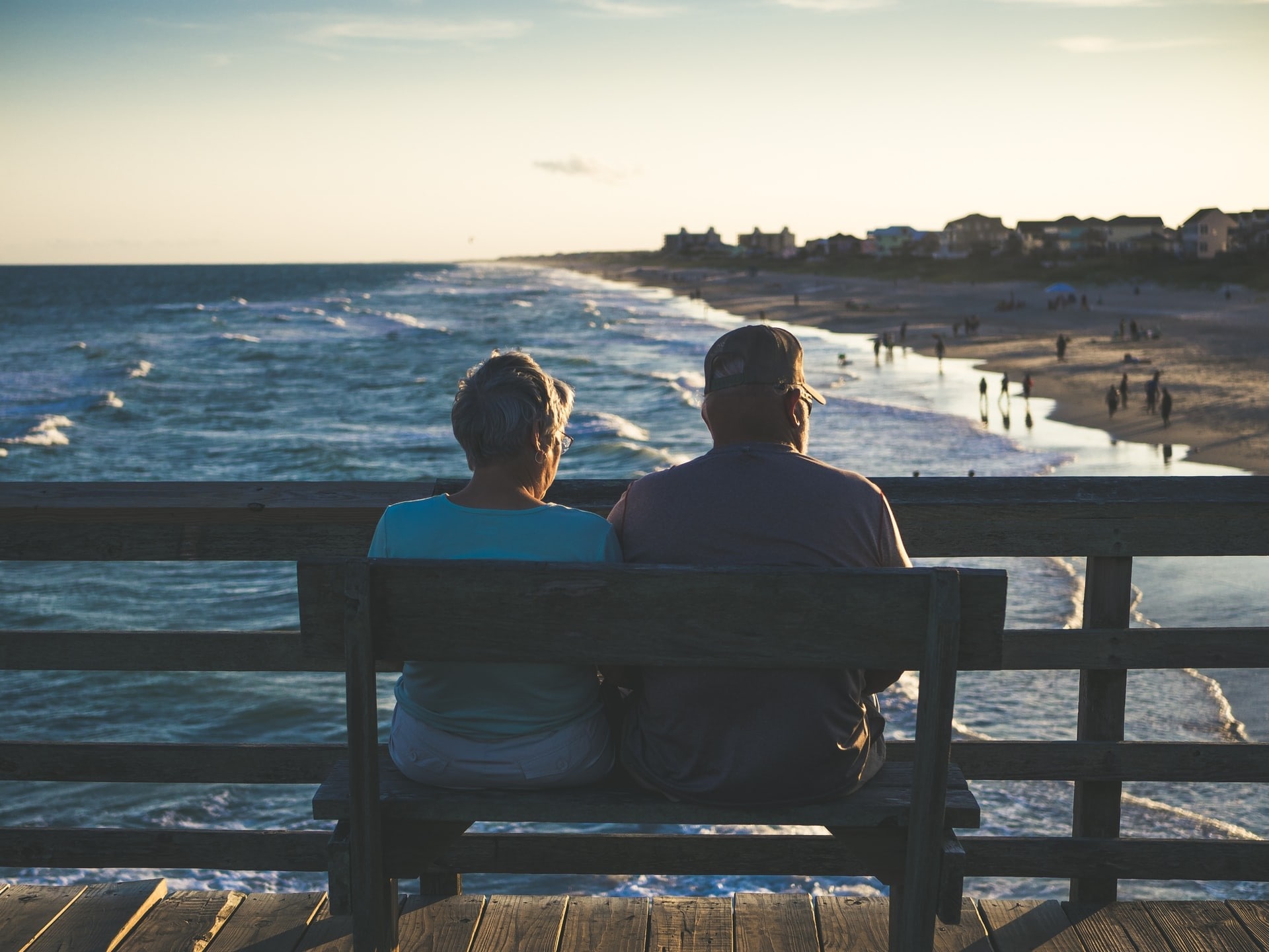 Elderly couple sitting on a pier by the ocean
