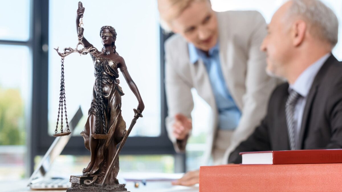 Justice statue and elder lawyers discussing case