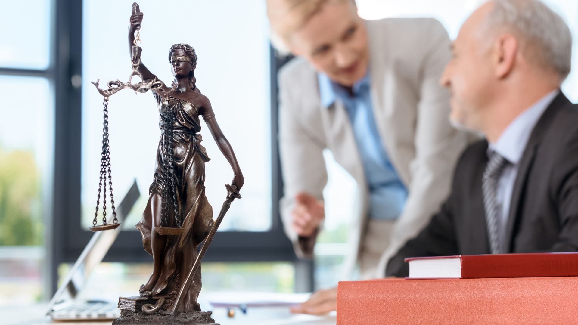 Justice statue and elder lawyers discussing case