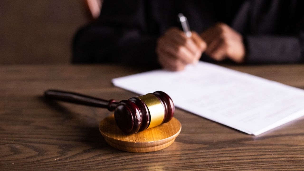 Judge writing elder law document with gavel on desk