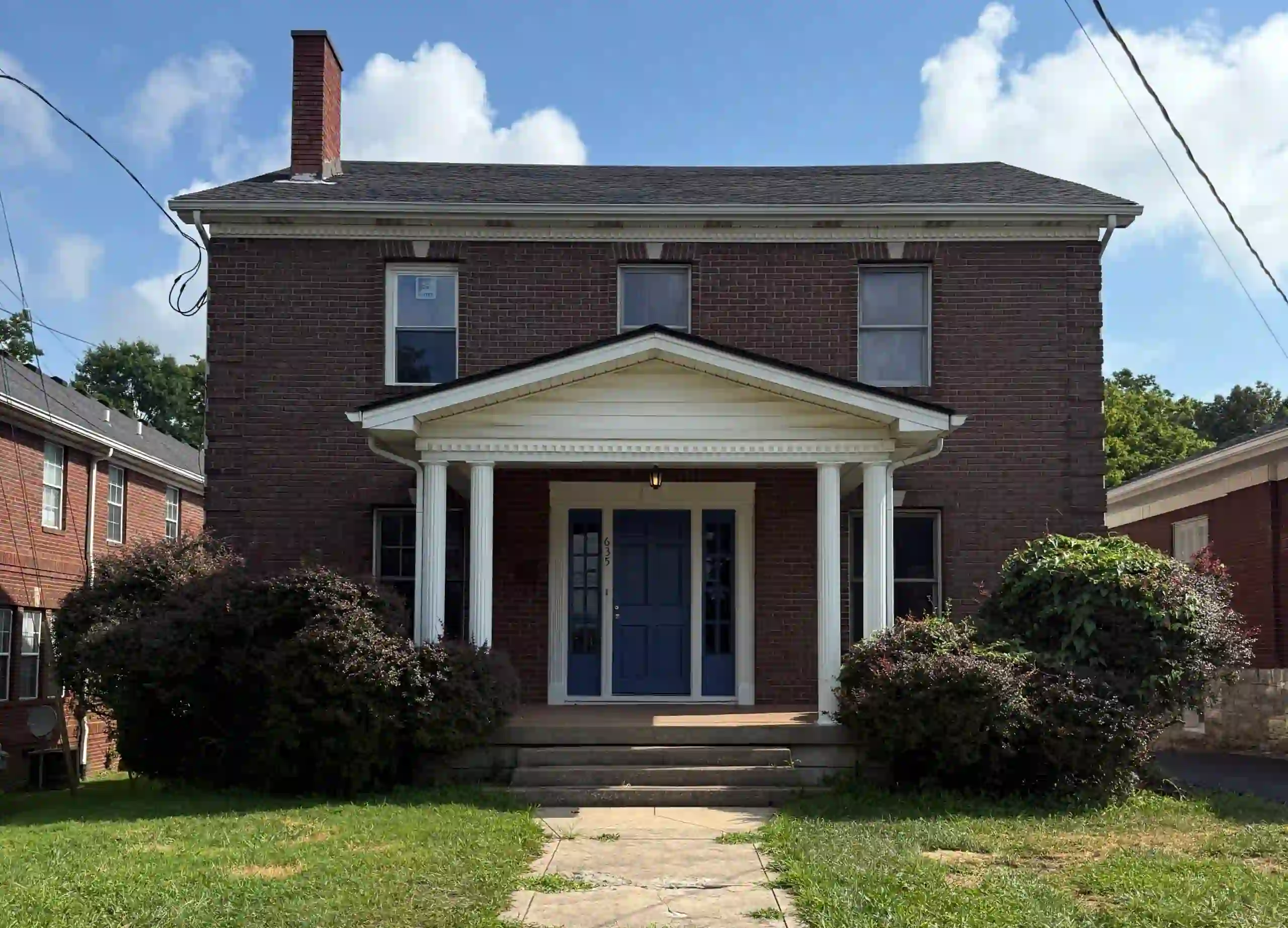 Brick house with white columns and blue door