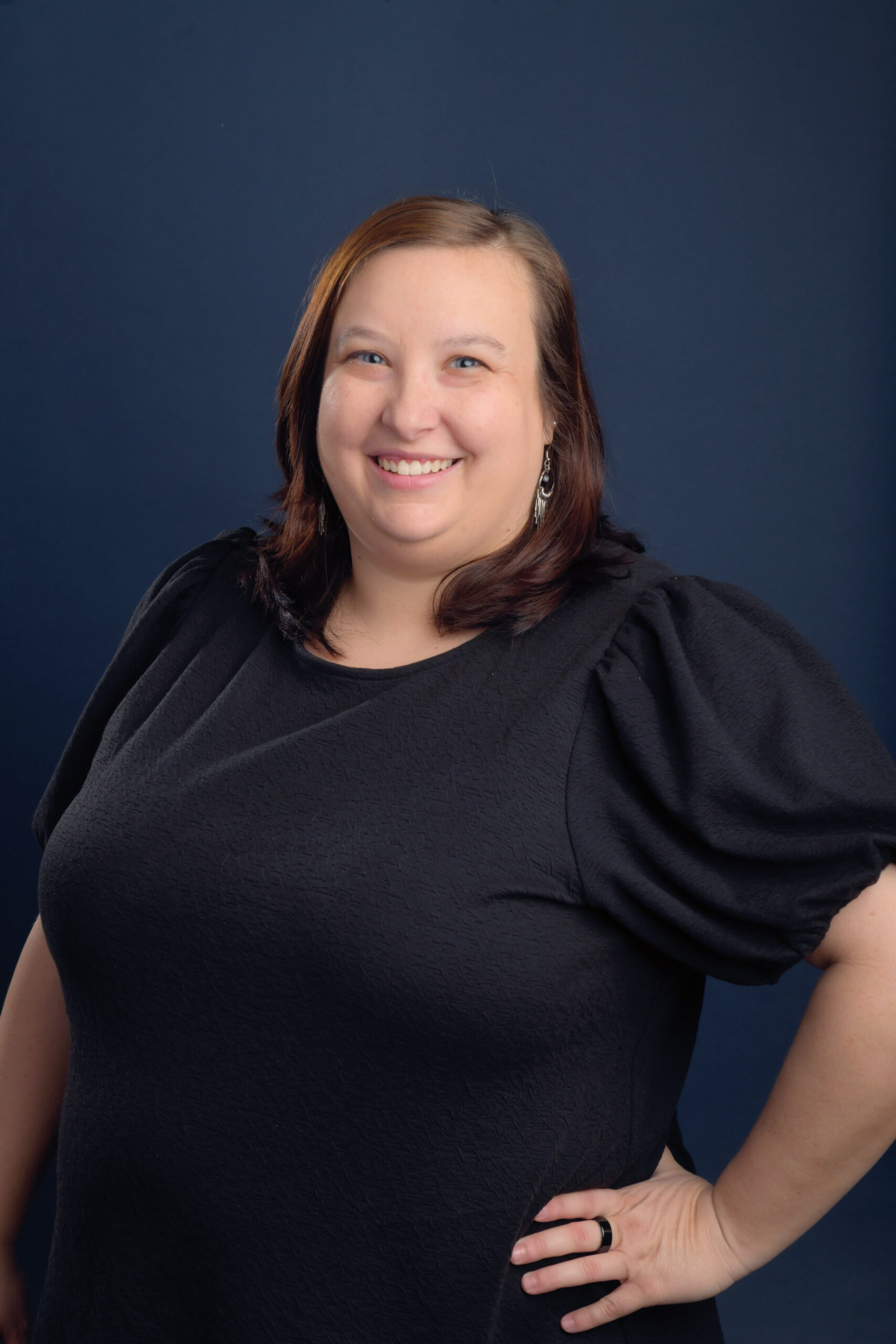 Smiling woman in black top against blue background