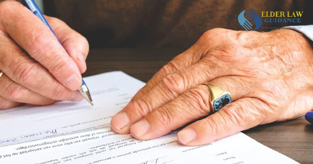 Close-up of a senior adult signing a legal document with a focus on hand and gold ring, illustrating estate planning lawyer in Corbin KY. Branded with the Elder Law Guidance logo.